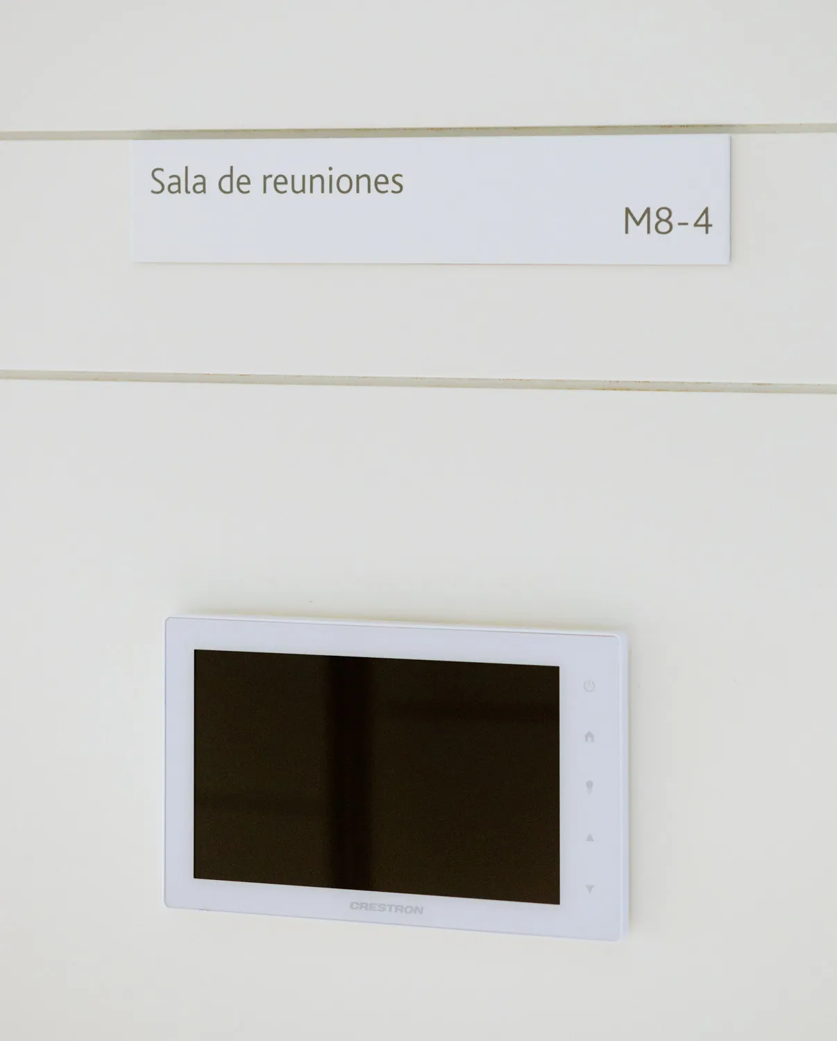 Pantalla táctil de reserva de salas instalada junto al rótulo de la sala de reuniones.